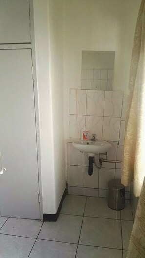 Um banheiro pequeno com pia branca, vaso sanitário e lixeira.
