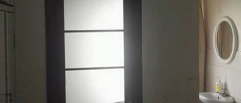 Una habitación con una puerta, un aire acondicionado, un lavabo y un espejo.