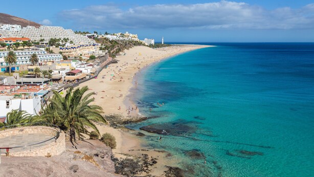 Eine Küstenstadt mit Strand, klarem blauen Wasser und Häusern entlang der Küste.