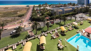 Ein Resort mit Pool, Liegestühlen und Blick auf Strand und Meer.
