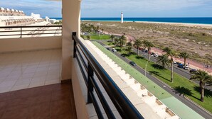 Ein Balkon mit Blick auf einen Strand, einen Leuchtturm und eine Straße mit Palmen.