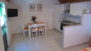 Una cuina compacta amb armaris blancs, una taula de dinar amb cadires i una petita illa amb una rentadora.