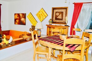 A dining area with wooden furniture, a table with a patterned tablecloth, and wall art.