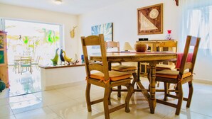 A dining area with a wooden table and chairs, a window with a view of palm trees, and a wall with a framed map. - Room-playacar - Superior Comfort Room Wi (Playa del Carmen)