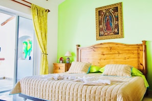 A bed with a wooden headboard, a green wall, and a framed picture above it.