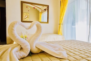 A hotel room with a bed, a mirror, and a decorative towel arrangement.