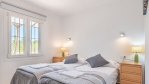 Un dormitorio con dos camas, mesitas de noche, lámparas y una ventana con vistas.