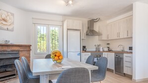 Una cocina moderna con una mesa de comedor, sillas, un frutero y un horno empotrado.