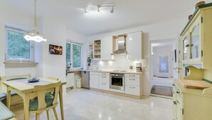 Una cocina moderna con armarios blancos, una mesa de comedor con sillas y una lámpara colgante.