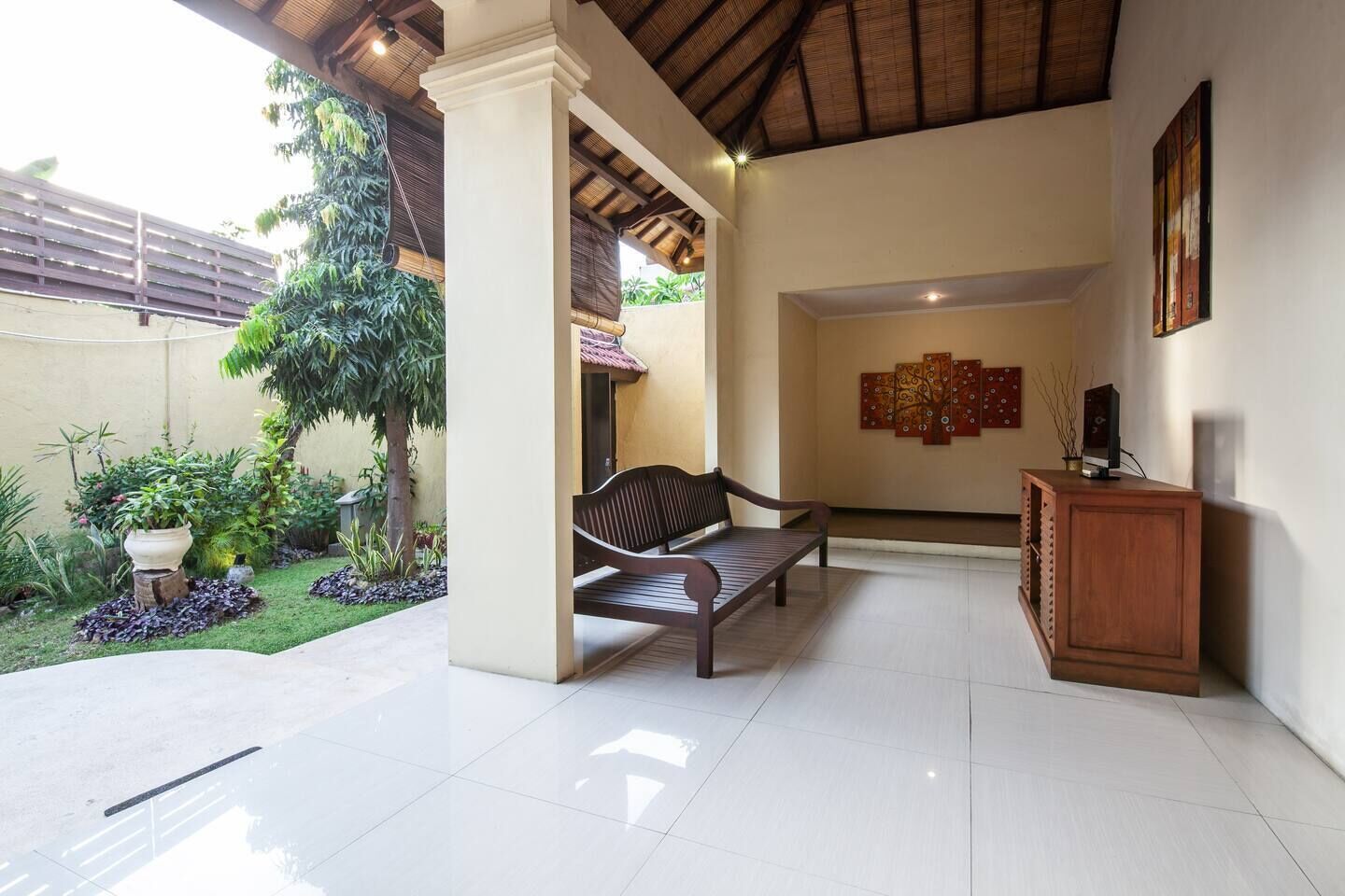 A spacious indoor area with a bench, a wooden cabinet, and a wall with artwork.