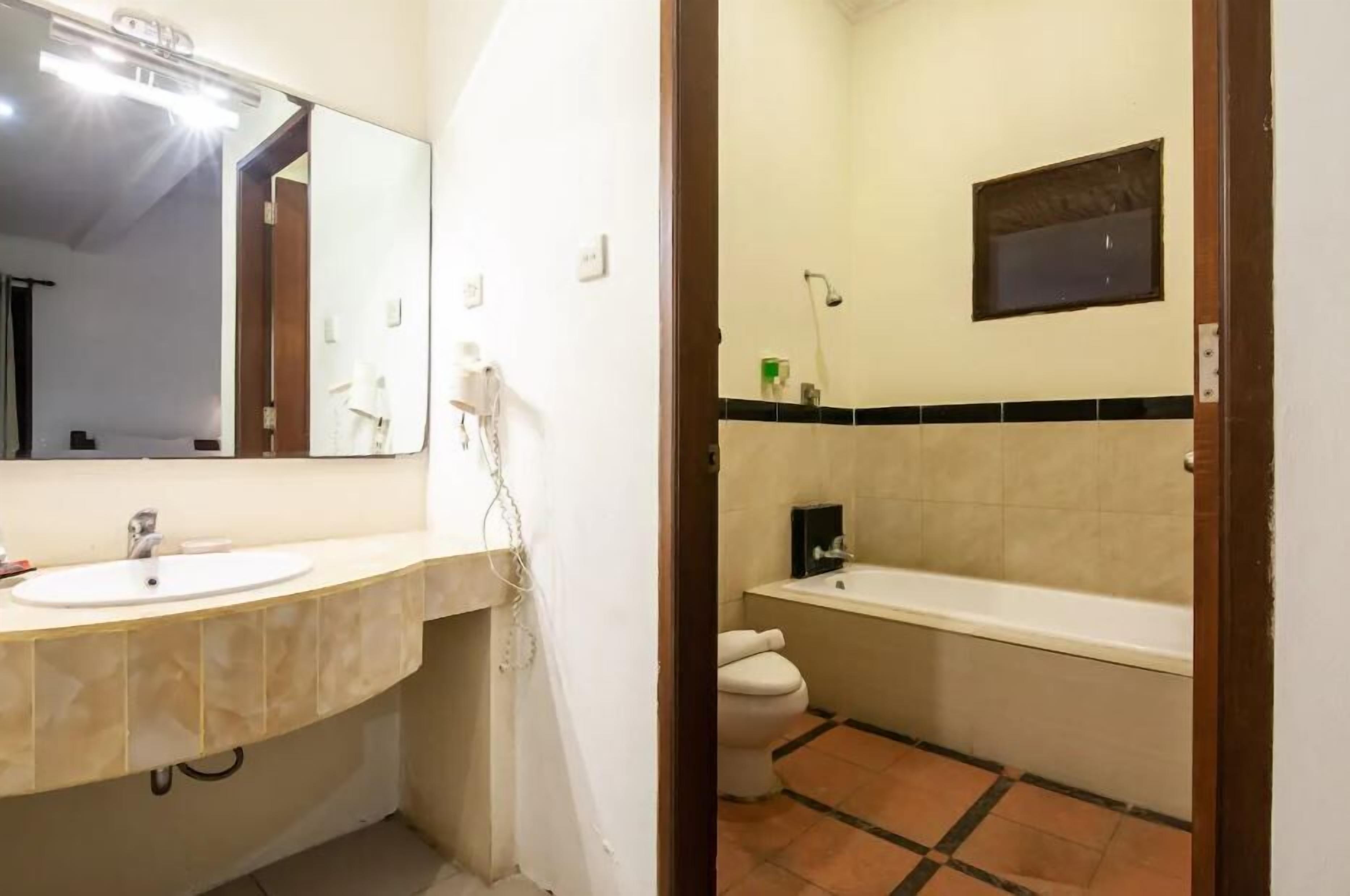 A bathroom with a sink, mirror, toilet, and bathtub.