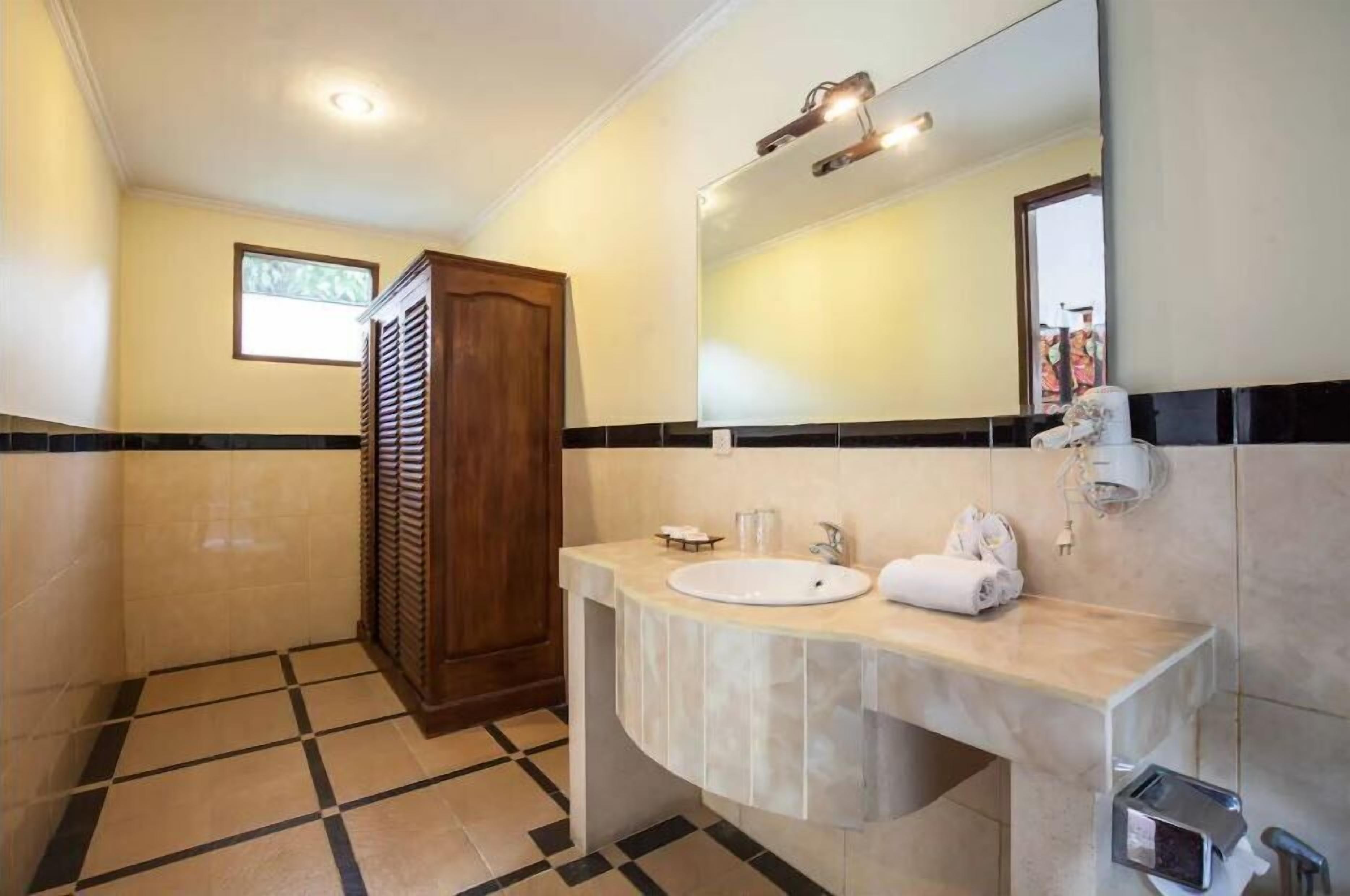 A bathroom with a sink, mirror, towel rack, and a shower area.