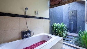Ein Badezimmer mit einer Badewanne, gefüllt mit Rosenblättern, einer Duschkabine und einem kleinen Garten mit Pflanzen.