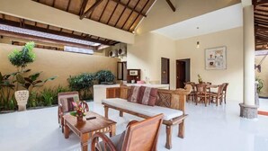 A spacious indoor area with a high ceiling, wooden furniture, and potted plants. - PB - Villa 5 - 4BR · 4-BR Private Pool Villa Walk to Seminyak Beach (Seminyak)