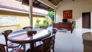 A spacious indoor area with a round table and chairs, a wooden bench, and a television.