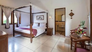 A four-poster bed with a wooden frame, a bedside table, and a chair with a vase of flowers.