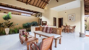 A spacious indoor area with a high ceiling, wooden furniture, and potted plants.