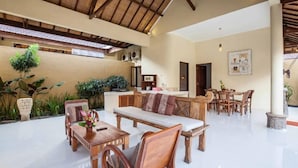 Un espace intérieur vaste, doté d’un plafond haut, de meubles en bois et d’une variété de plantes.