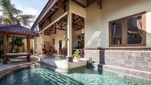 Ein Poolbereich mit Pergola, Sitzgelegenheiten und einer Steinmauer.