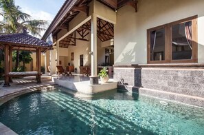 A pool area with a pergola, seating, and a stone wall. - PB - Villa 2 - 2BR · 2-BR Private Pool Villa Walk to Seminyak Beach (Seminyak)