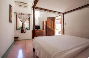 A bedroom with a four-poster bed, a television, and a wardrobe.