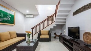 A modern living room with a sofa, two armchairs, a coffee table, a TV, and a staircase. - SMV - 3BedGRDN - V1 · 3BR Garden Villa Walk to Beach N Shops Legian (Legian)