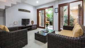 A living room with wicker furniture, a flat-screen TV, and a glass coffee table. - SMV - 3BedGRDN - V1 · 3BR Garden Villa Walk to Beach N Shops Legian (Legian)