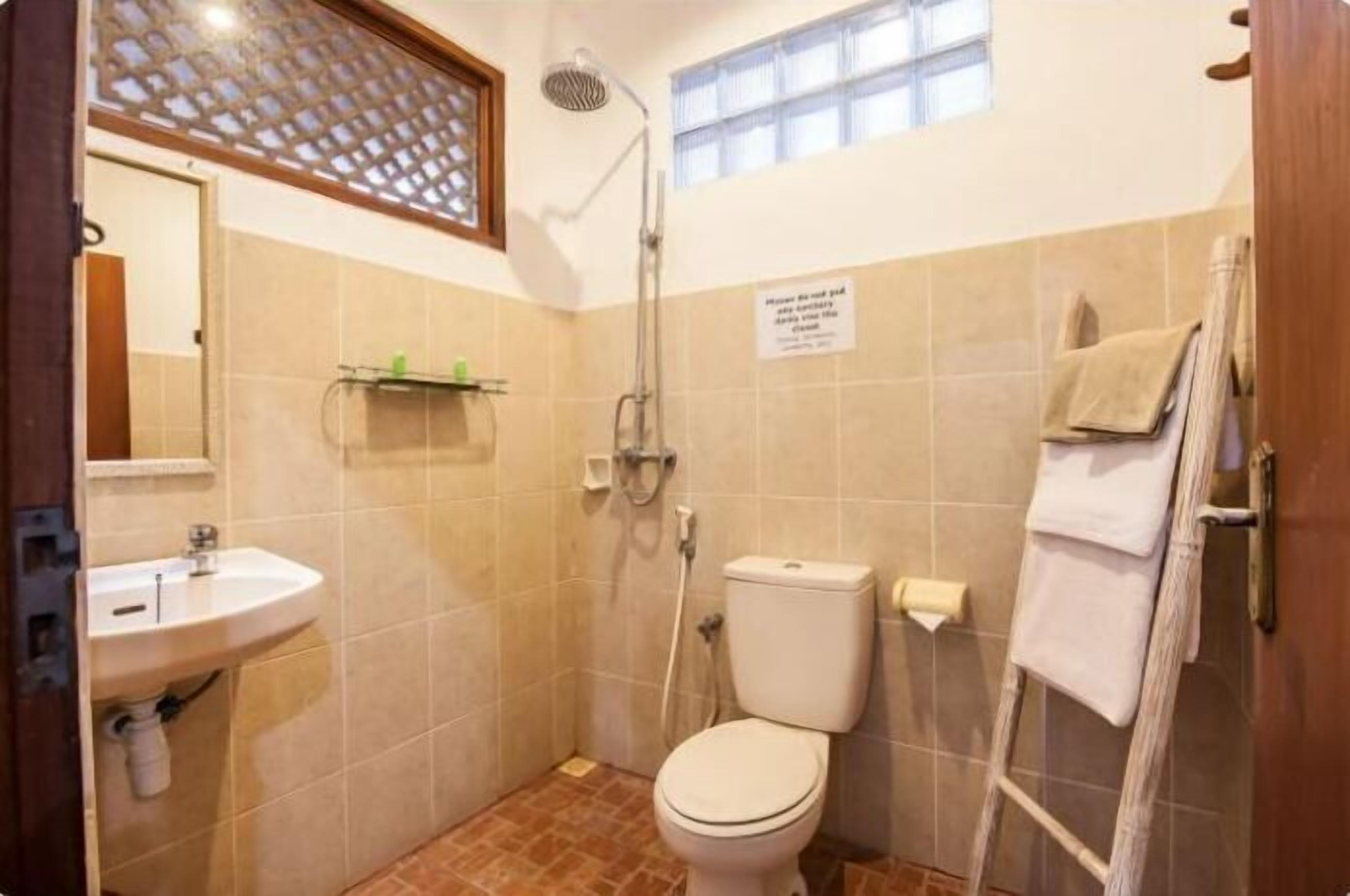 A small bathroom with a toilet, sink, and shower.
