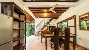 A dining area with a wooden table and chairs, a ceiling fan, and a staircase leading to another level. - SMV- 2BedGRDN - V6 · 2BR Garden Villa Walk to shops and Beach Legian (Legian)