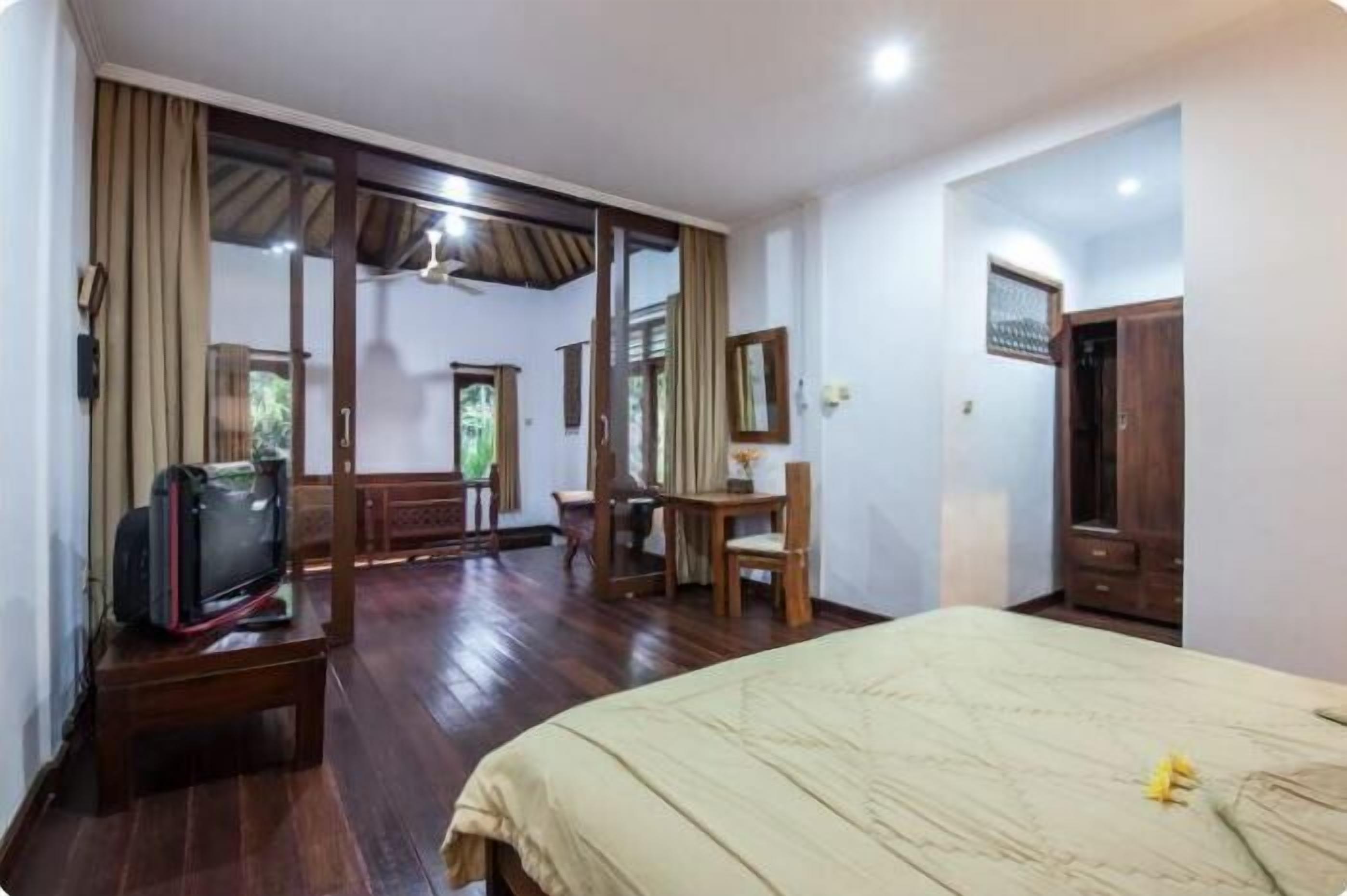 A hotel room with a bed, a desk, a chair, and a television.