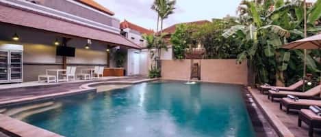 A swimming pool with lounge chairs and a bar area.