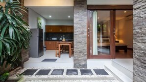 A modern kitchen with a refrigerator, wooden cabinets, and a dining area.