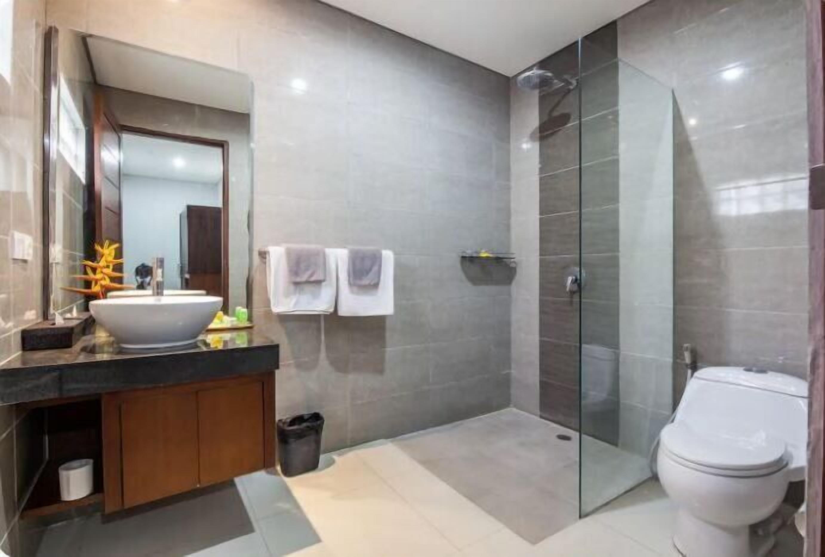 Une salle de bain moderne avec un grand lavabo, une douche à parois de verre et des toilettes.