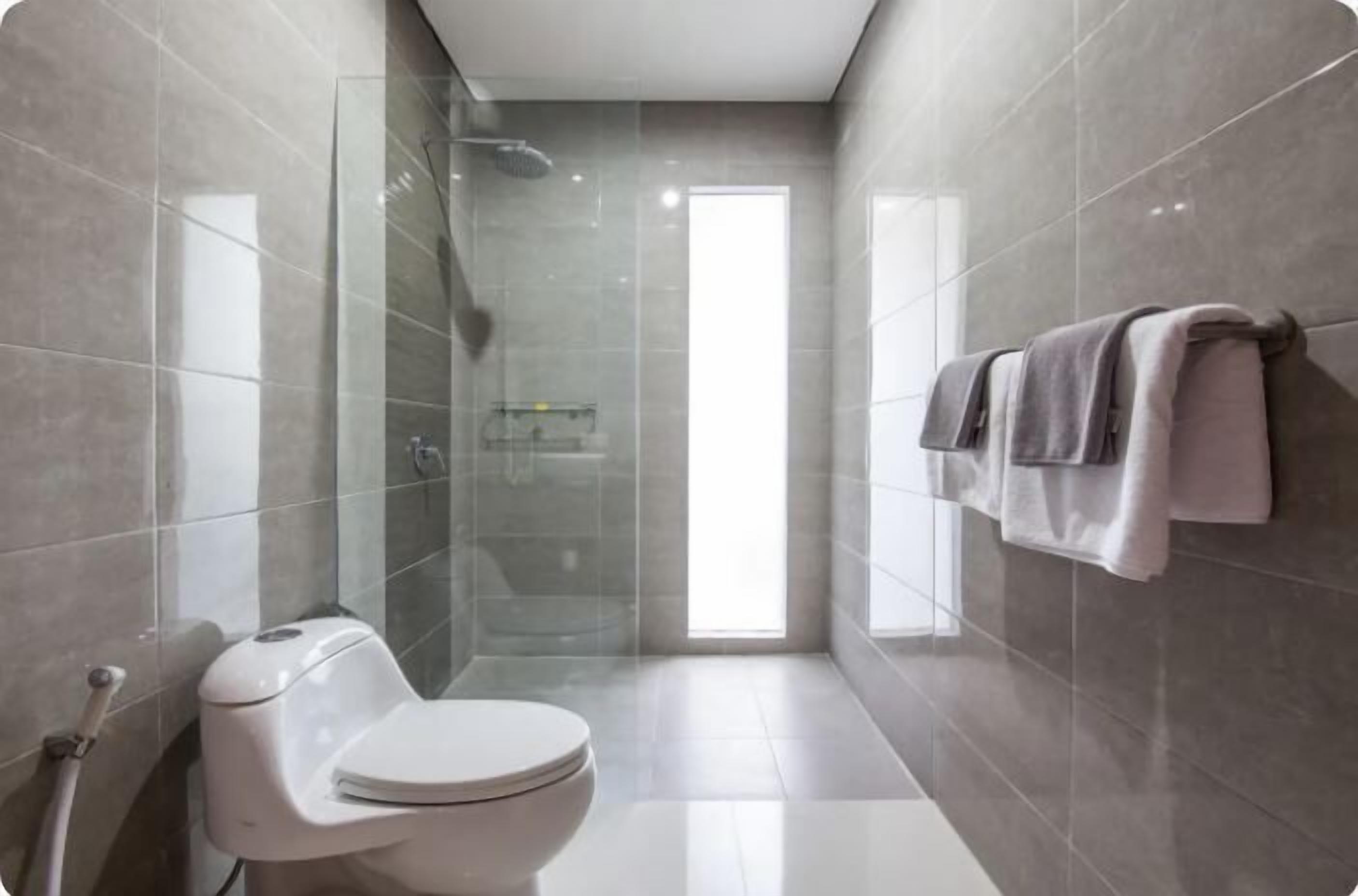 A modern bathroom with a toilet, shower, and glass-enclosed shower area.