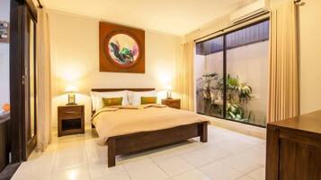 A bedroom with a large bed, bedside tables, a wall-mounted artwork, and a view through a large window.