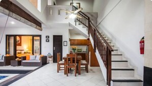 Un vaste espace de vie comprenant une table et des chaises, un escalier et une cuisine ouverte.