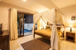 A bedroom with a four-poster bed, a bedside table, a lamp, and a view of a pool through a glass door.