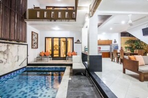 A modern interior with a swimming pool, a dining area, and a kitchen.