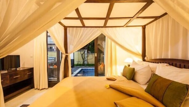 Una habitación con cama, cortinas, mesita de noche y vista a una piscina.
