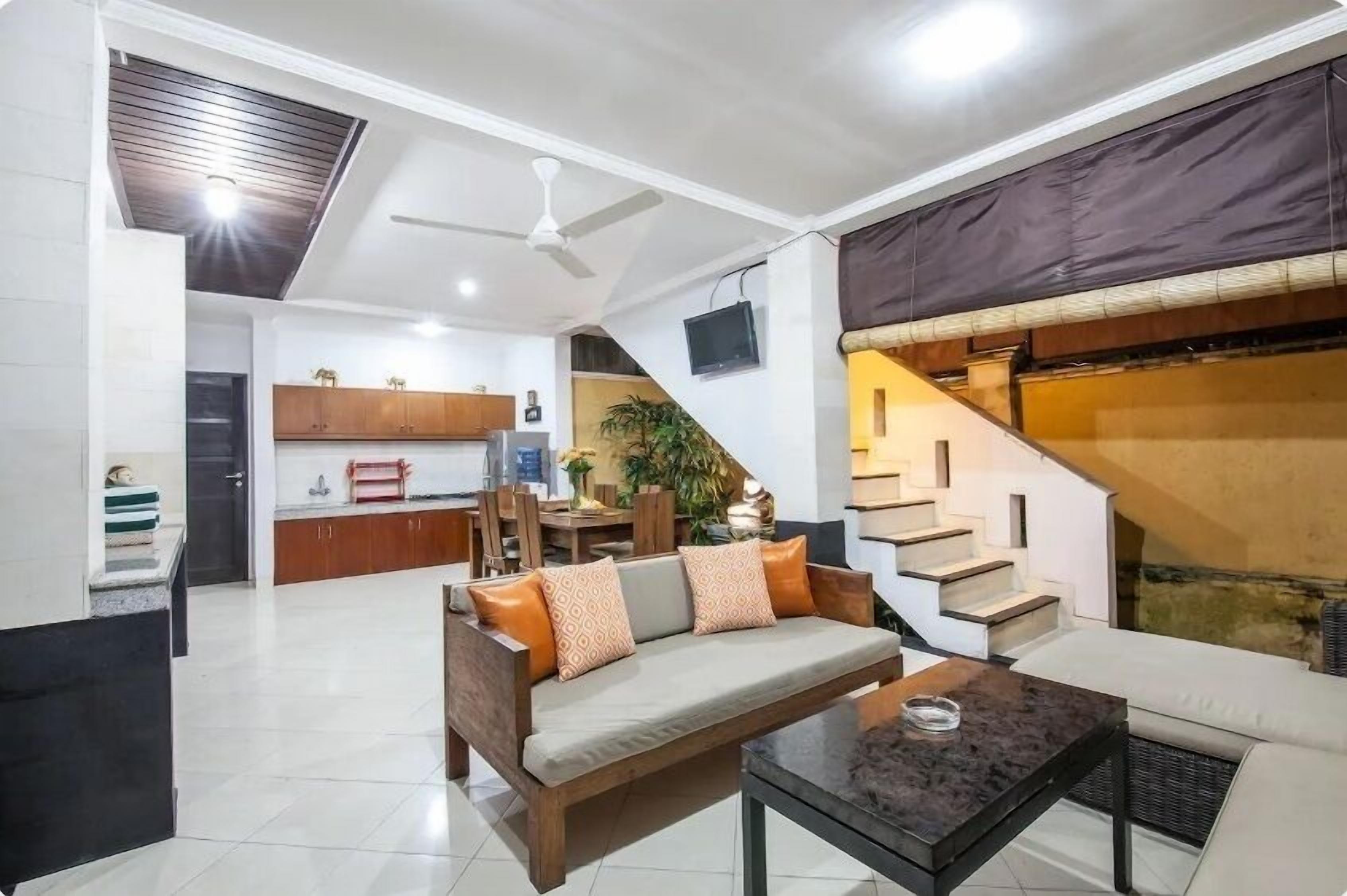 A spacious living area with a sofa, a coffee table, and a staircase leading to a kitchen.
