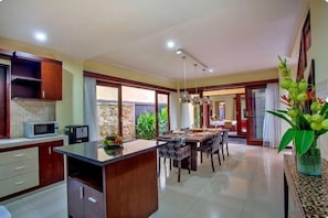 A modern kitchen with a central island, dining area with chairs, and a large window.