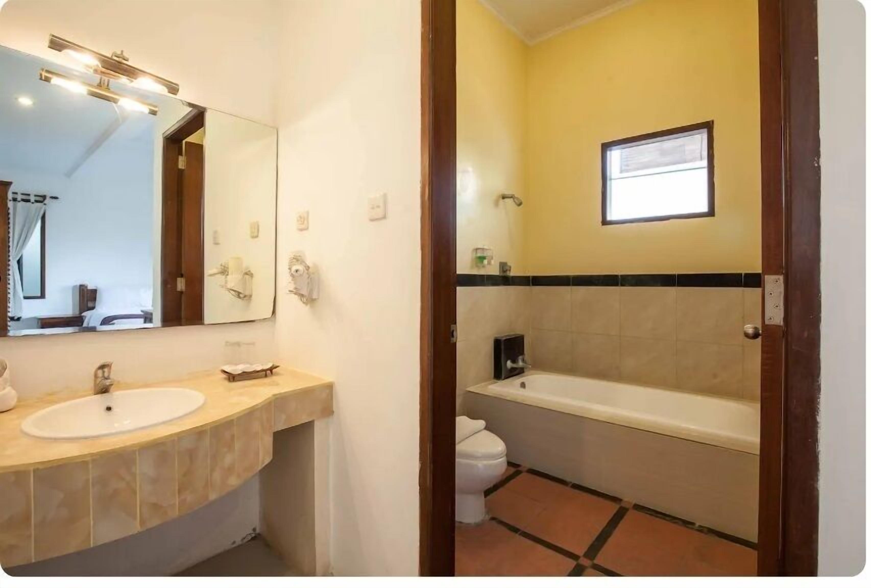 A bathroom with a sink, mirror, and bathtub.