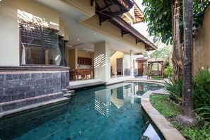 A swimming pool with a stone border, a wooden deck, and a covered outdoor seating area. - 4 Bathroom Private Pool Villa near Seminyak Beach Bali (Seminyak)