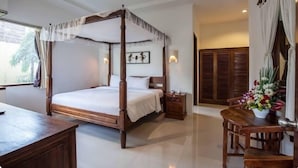 A four-poster bed with a canopy, a wooden nightstand, a desk, and a chair.