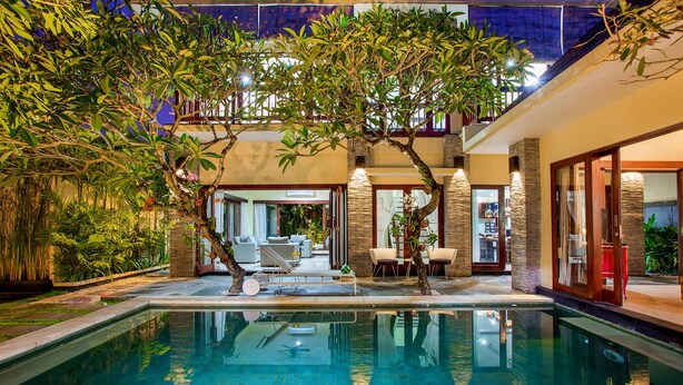 An indoor swimming pool with a lounge area, surrounded by greenery and stone walls. - Samudra - 1 · 1BR Luxury Private Pool Villa Bali (Kerobokan)