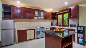 A modern kitchen with wooden cabinets, a central island, a refrigerator, stove, microwave, and a sink. - Samudra - 1 · 1BR Luxury Private Pool Villa Bali (Kerobokan)