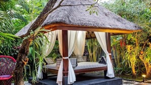 A thatched-roof gazebo with a bed, surrounded by lush greenery. - Samudra - 1 · 1BR Luxury Private Pool Villa Bali (Kerobokan)