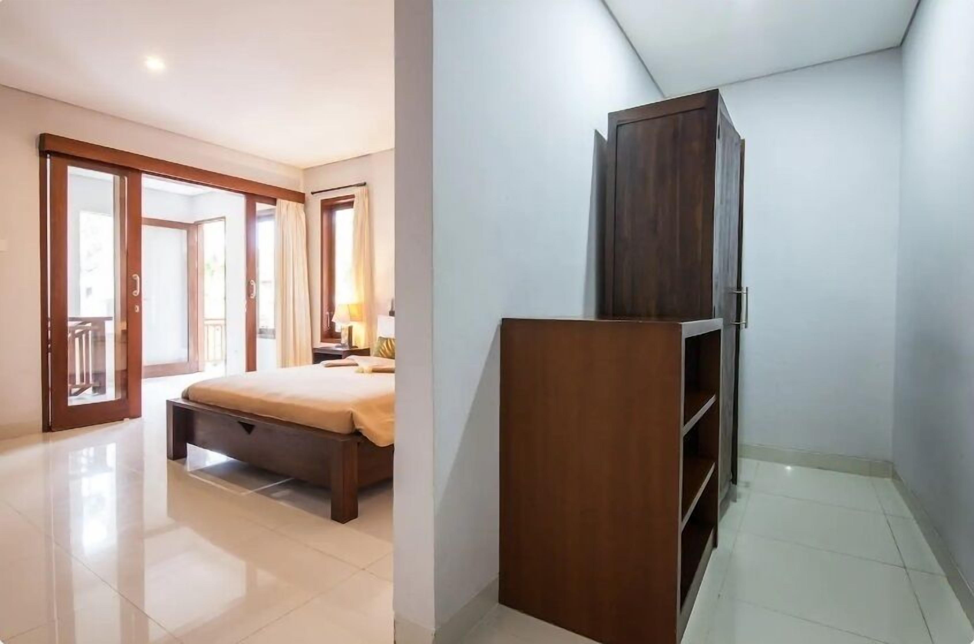 Un dormitorio con cama, armario y puerta que da a un balcón.