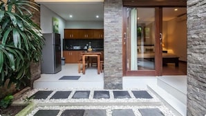 A modern kitchen with dark cabinets, a refrigerator, and a dining area with a table and chairs. - SMV - garden - 8-BR · 8BR Garden Villa Walk to Beach and Shops Legian (Legian)