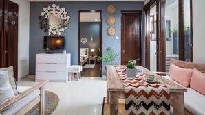 Ein modernes Wohnzimmer mit einem weißen Sofa, einem Holztisch und einem Fernseher auf einem Lowboard.